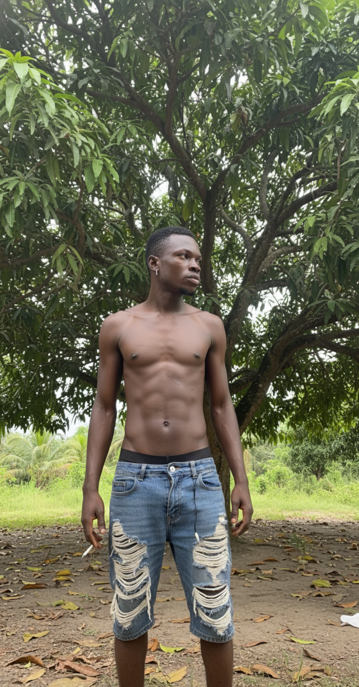 I'm shirtless in a minimalist outdoor setting, wearing low-slung, ripped blue denim shorts  that are unbuckled and sagging. He holds a cigarette between his fingers, looking away from the camera with a serious expression. contrasting with the outdoor tropical context implied—Suriname’s Brokopondo, under a mango tree. The scene blends casual, gritty realism with a hint of urban street style, captured in a medium shot with natural lighting.